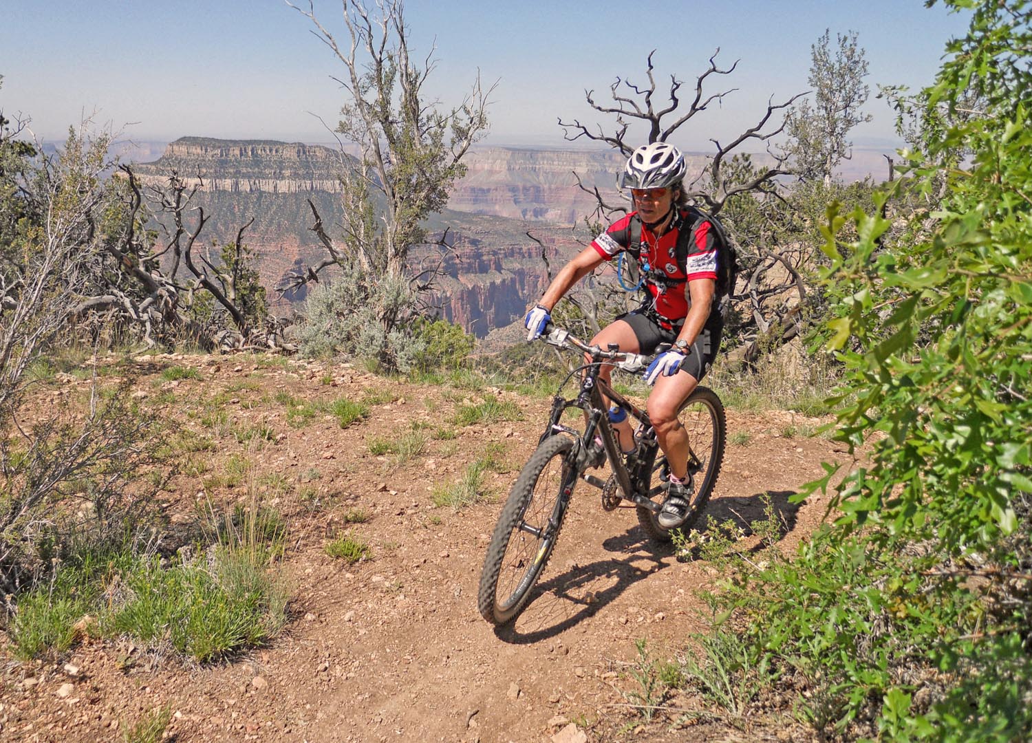 Jean rides a mountain bike on the edge of a steep canyon