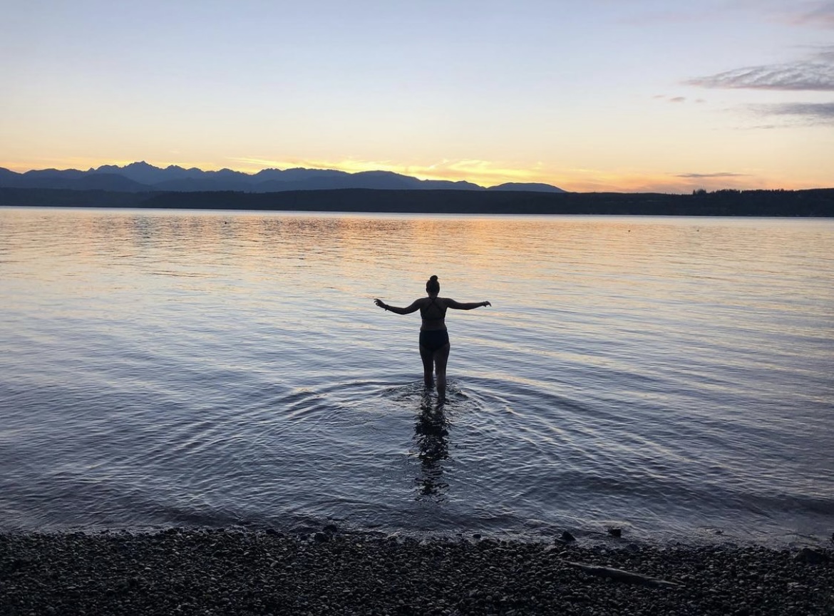 Woman standing in water at sunrise